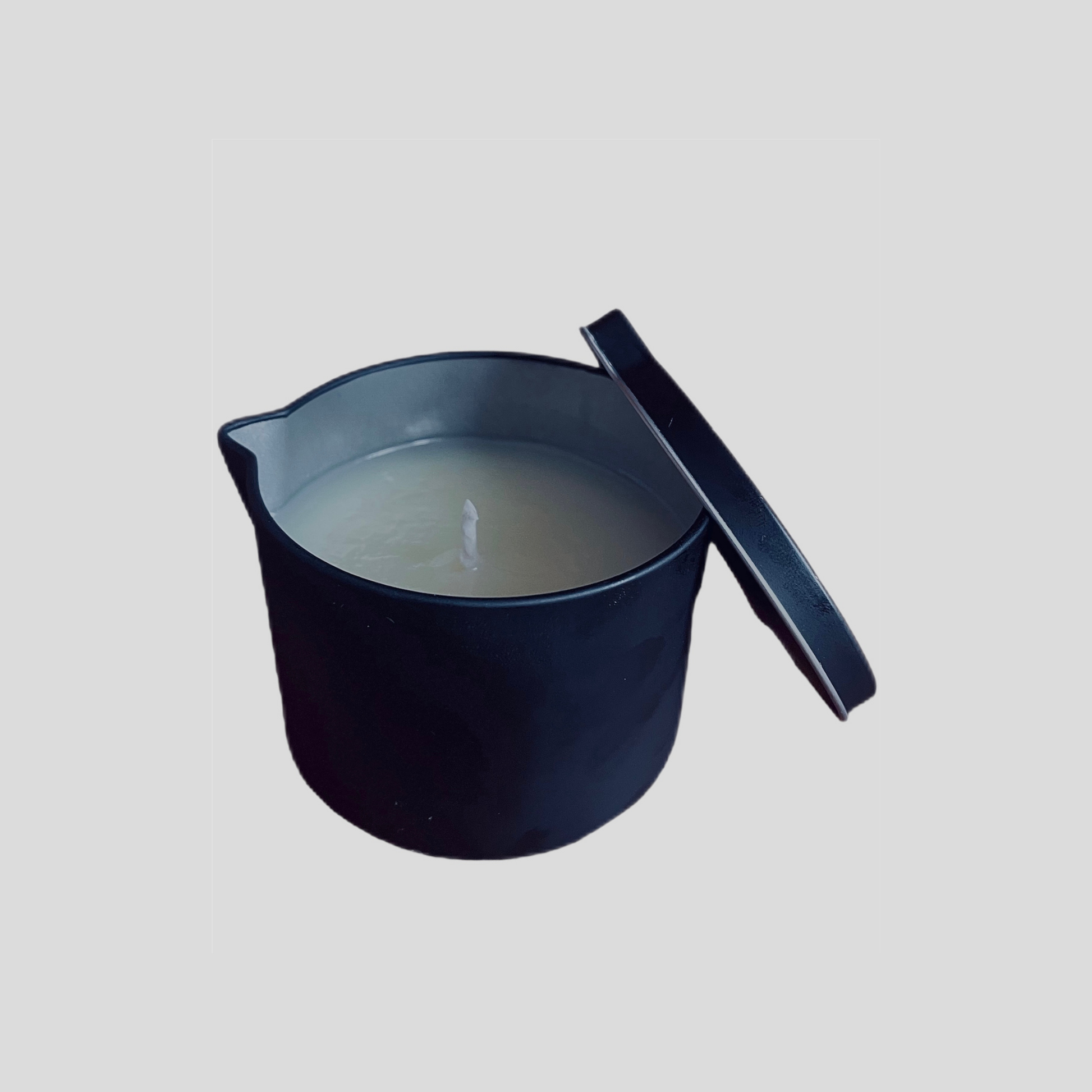 Autahi body serum candle tin with pourer and lid leaning to side of tin