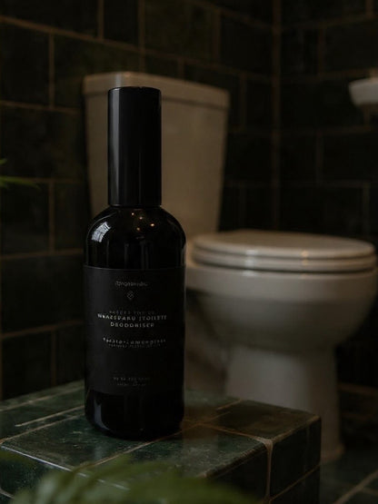 Wharepaku toilet deodoriser spray in 120ml sleek black glass bottle, designed to spray into toilet water before use to prevent odors.