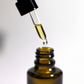 Face oil dropper holding golden face oil over bottle
